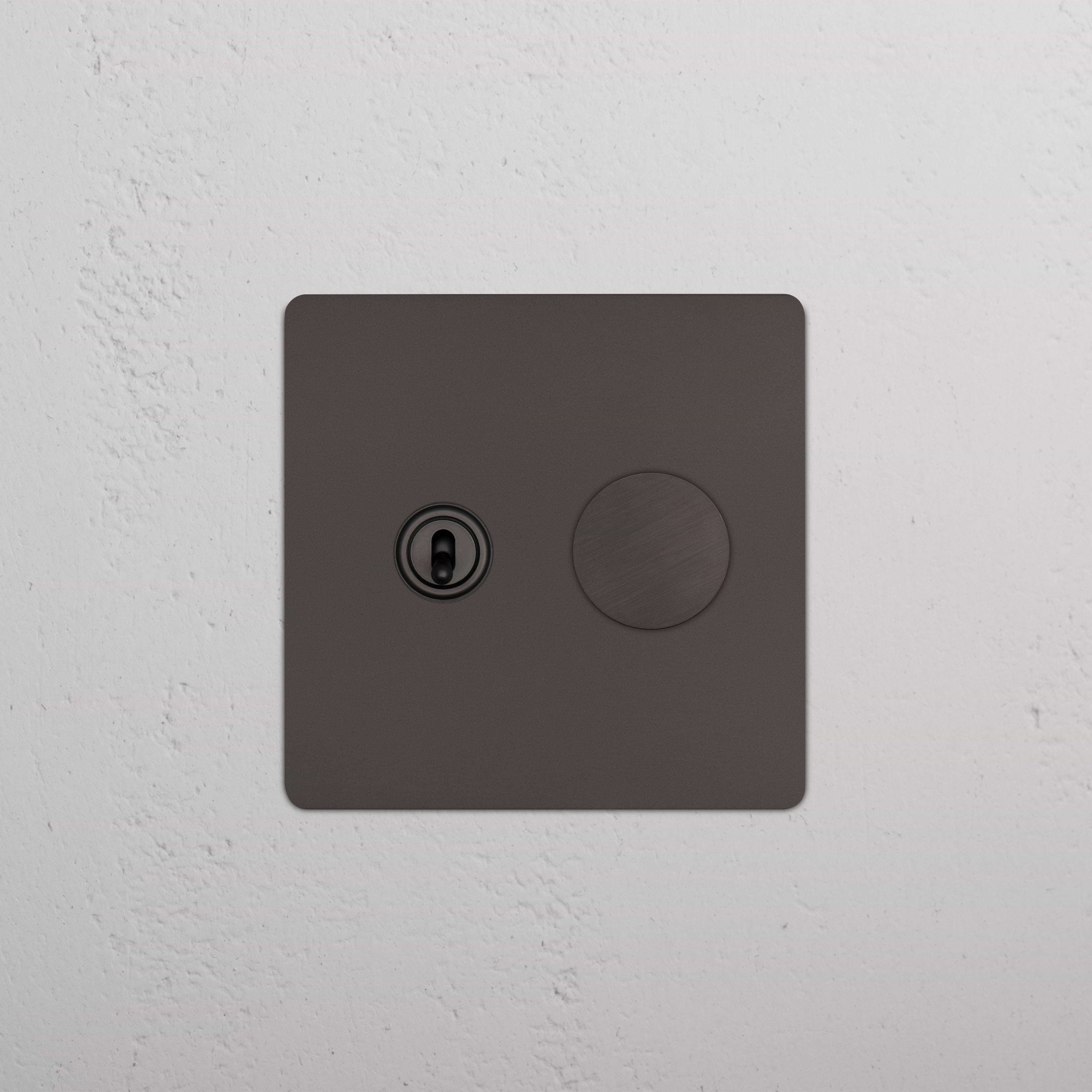 Kew 2G Toggle & Dimmer Switch in bronze, showing one toggle and one dimmer knob on a white wall.