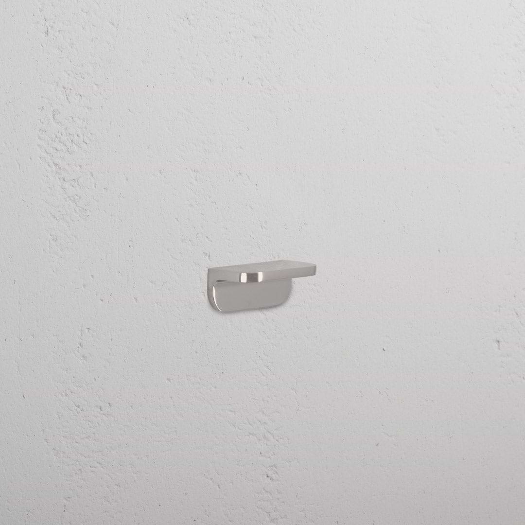 Oxford Furniture Handle Extra Small in polished nickel, mounted on a textured white wall.