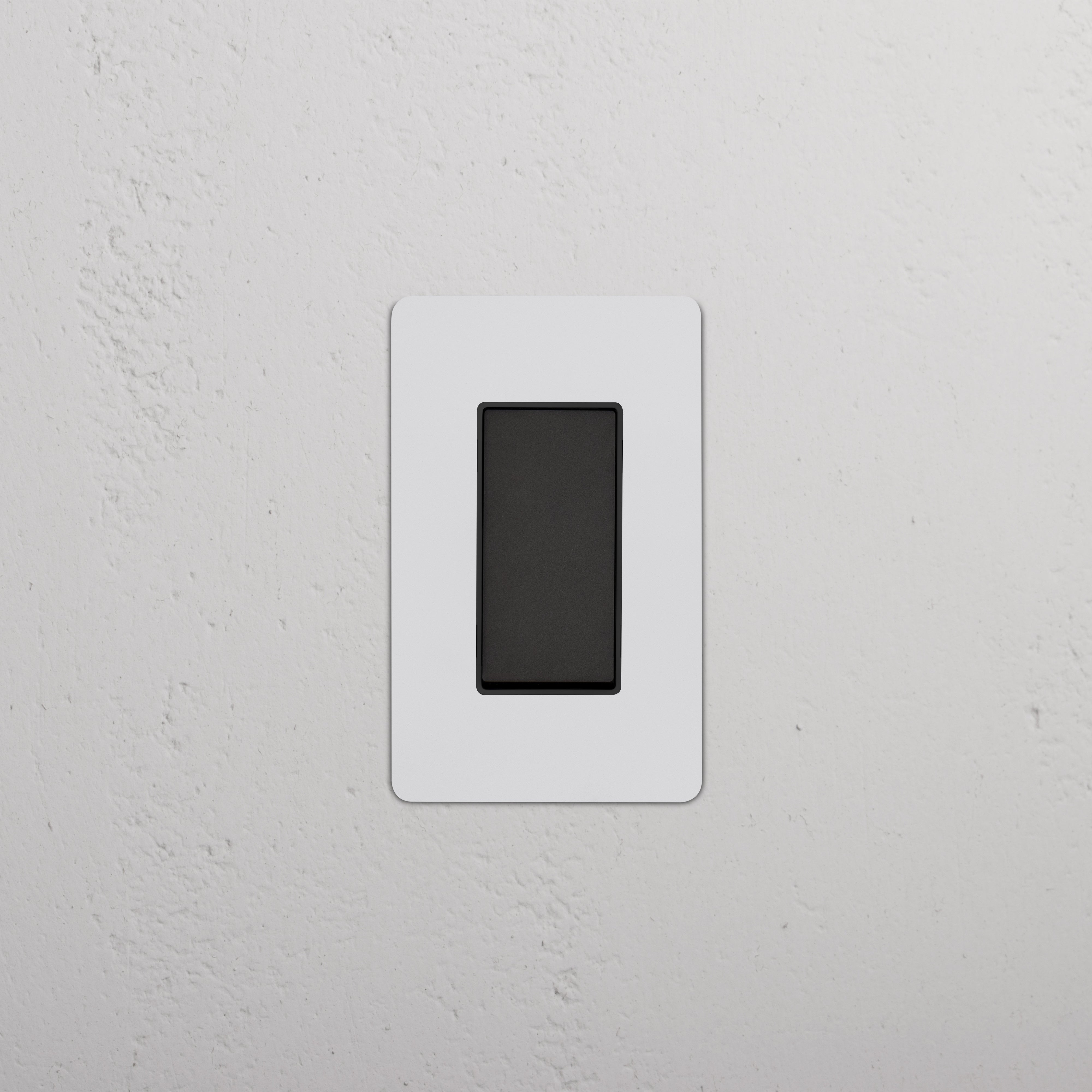 Kew 1G Four Way Rocker Switch in Paintable Bronze Black, installed on a white textured wall.