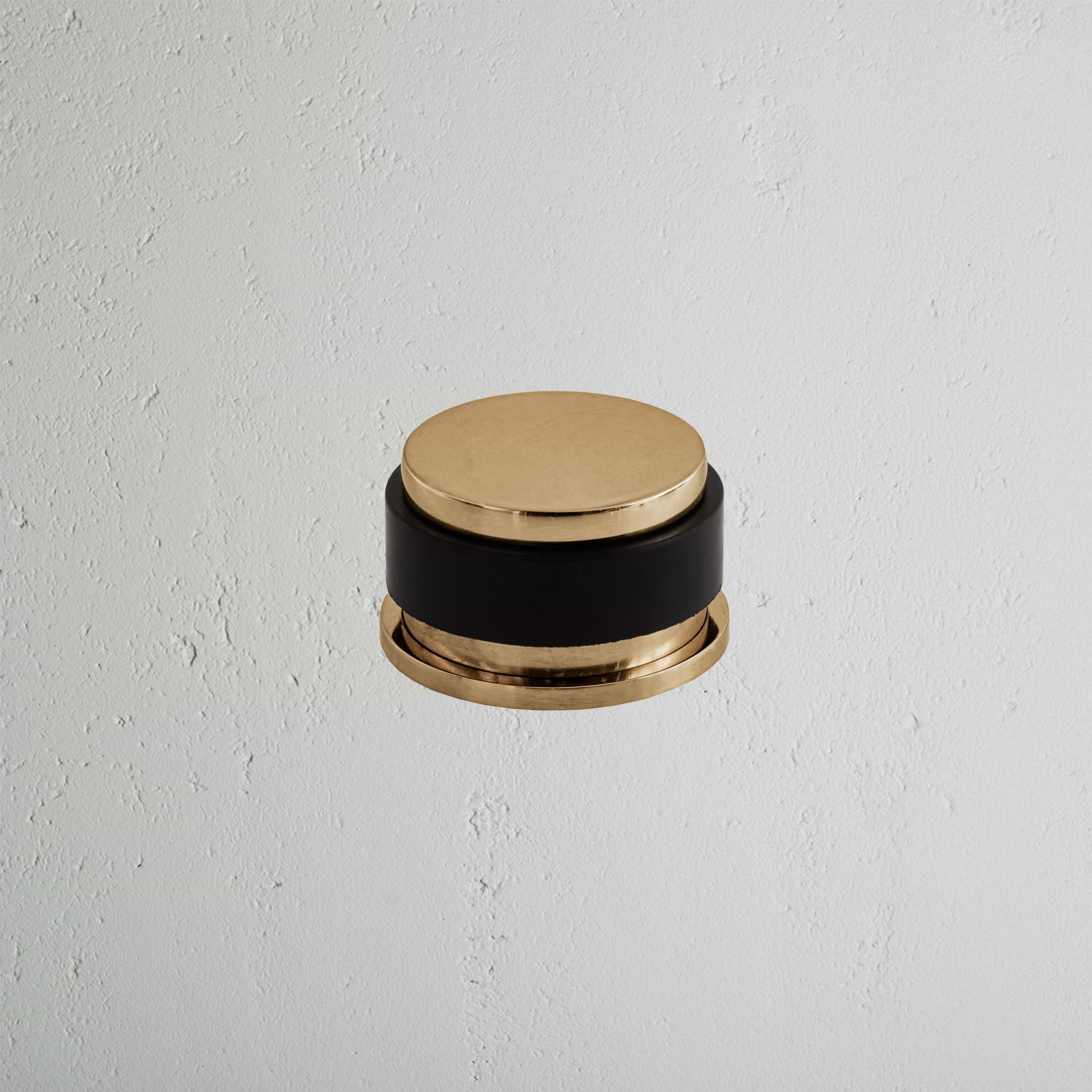 Seymour Door Stop in antique brass finish, mounted on a white textured wall.