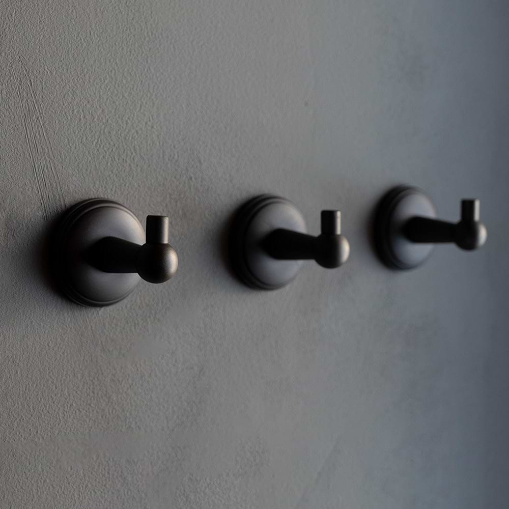Hyde Hook in bronze finish with a round base and modern design, mounted on a gray wall.