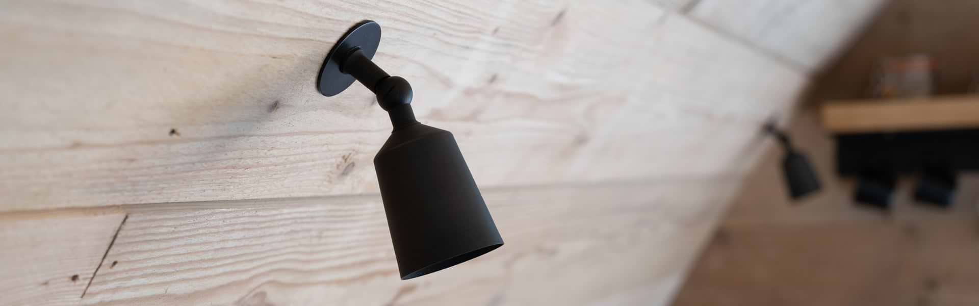 A single bronze black ceiling spotlight fixture is mounted on a white textured ceiling, angled downward toward the right.
