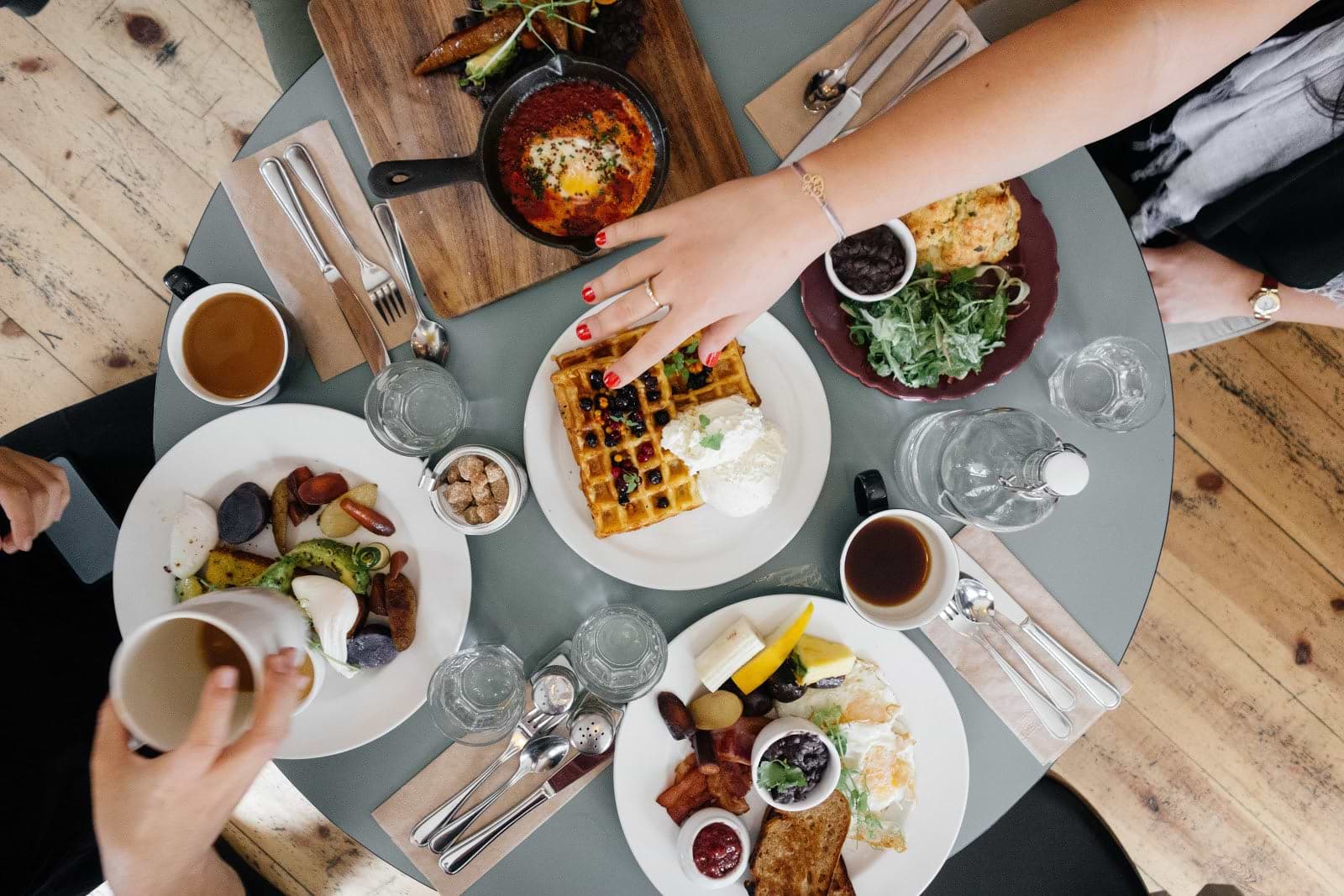 How to get rid of bloating: A table of people eating rich breakfast foods