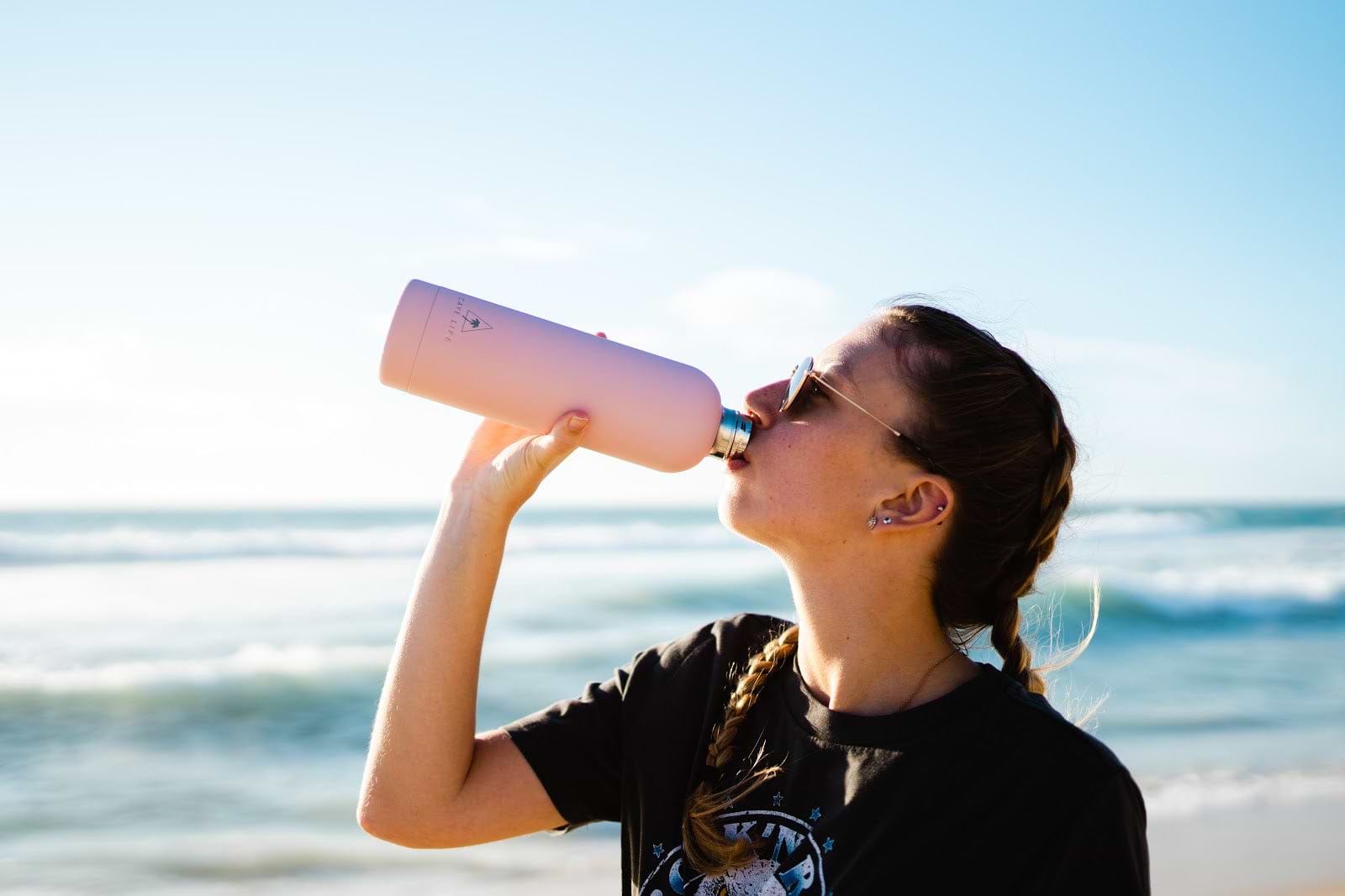 A woman drinks electrolyte keto supplements from a water bottle