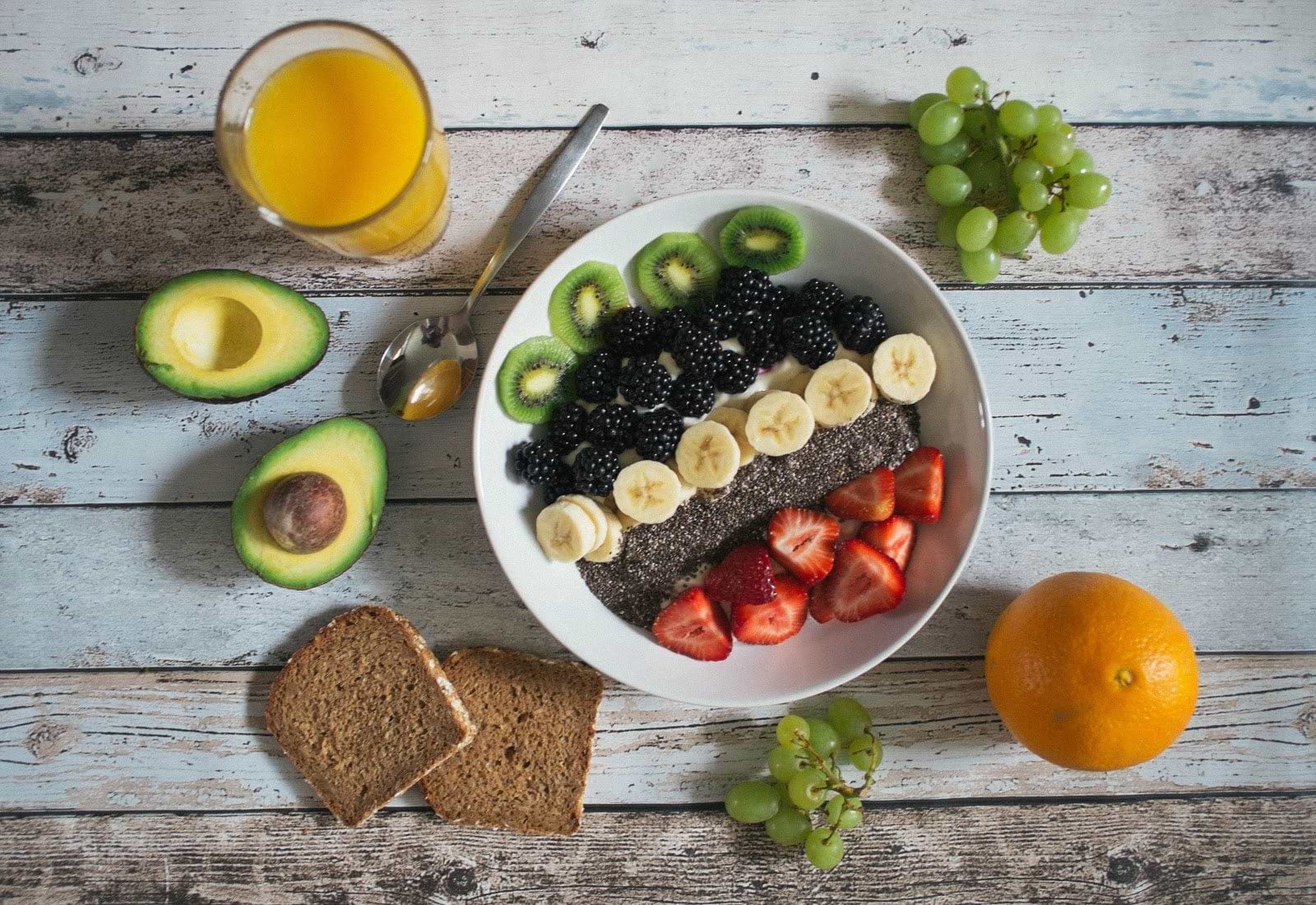 How to get rid of bloating: a bowl of fresh fruit and a glass of orange juice
