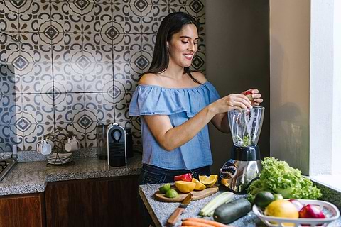 woman preparing veggie and fruit smoothie for detoxifying