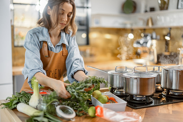 Young woman learning how to treat SIBO naturally and cooking healthy foods.