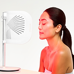 CurrentBody LED light therapy panel in front of a woman during skin treatment