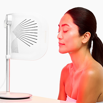 CurrentBody LED light therapy panel in front of a woman during skin treatment