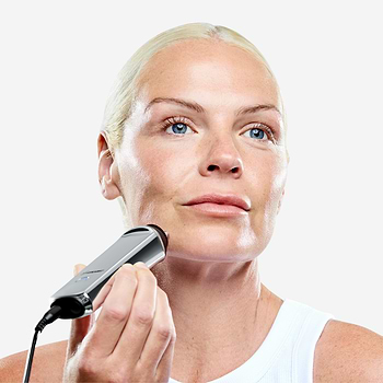 Mature woman demonstrating use of CurrentBody RF radio frequency device for facial skin firming