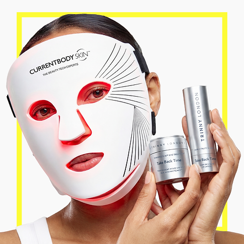 Woman wearing the Series 2 Red Light Mask and holding Trinny London products