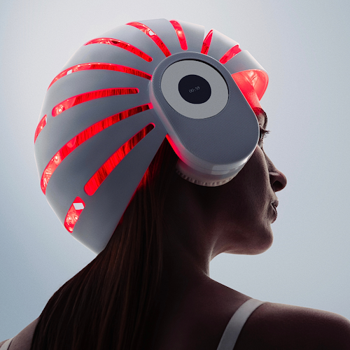 Woman using a red light therapy helmet for simulating hair growth naturally