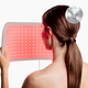 CurrentBody LED light therapy panel being held in front of her face for treatment