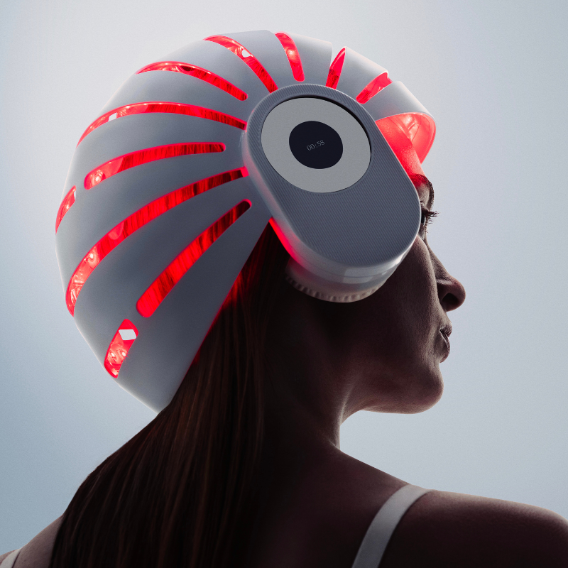 Woman using a red light therapy helmet for simulating hair growth naturally