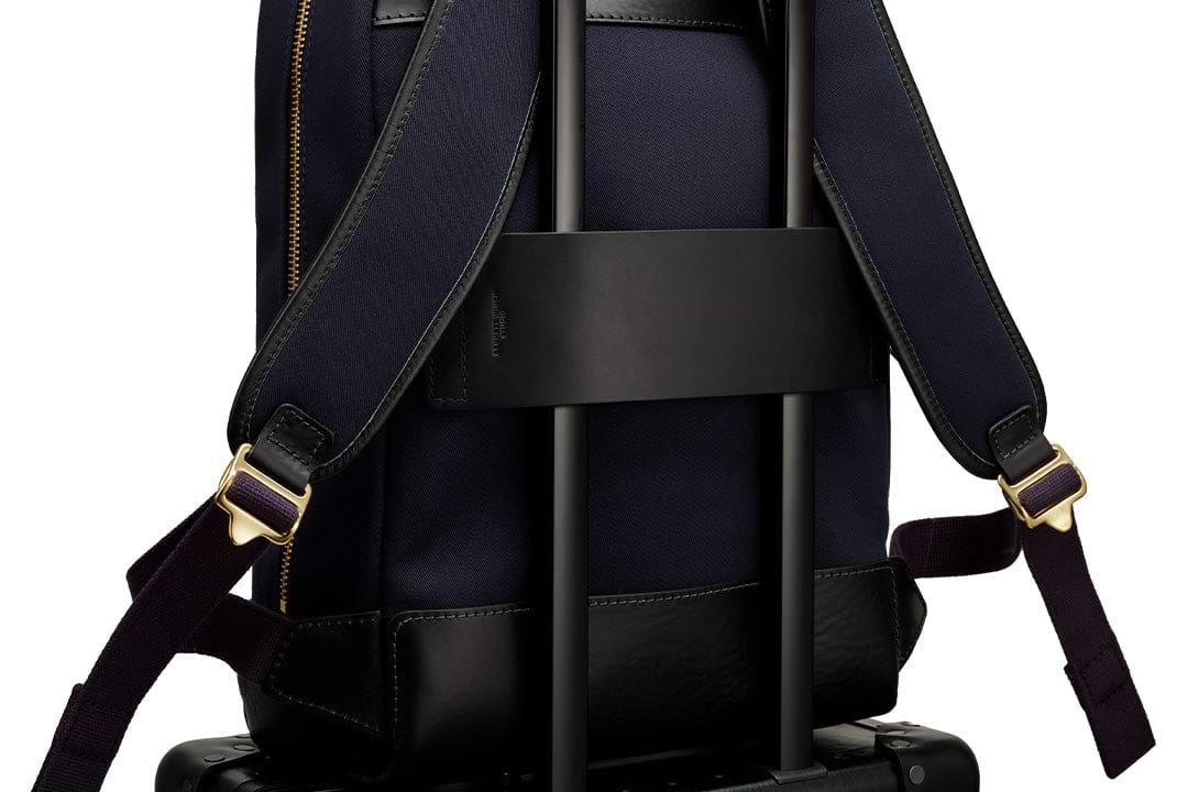 a close up of the luggage strap on the navy backpack 