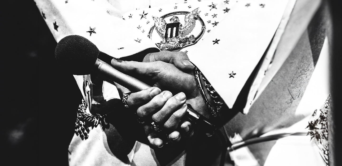 A person holding a microphone wearing an ornate costume adorned with stars.