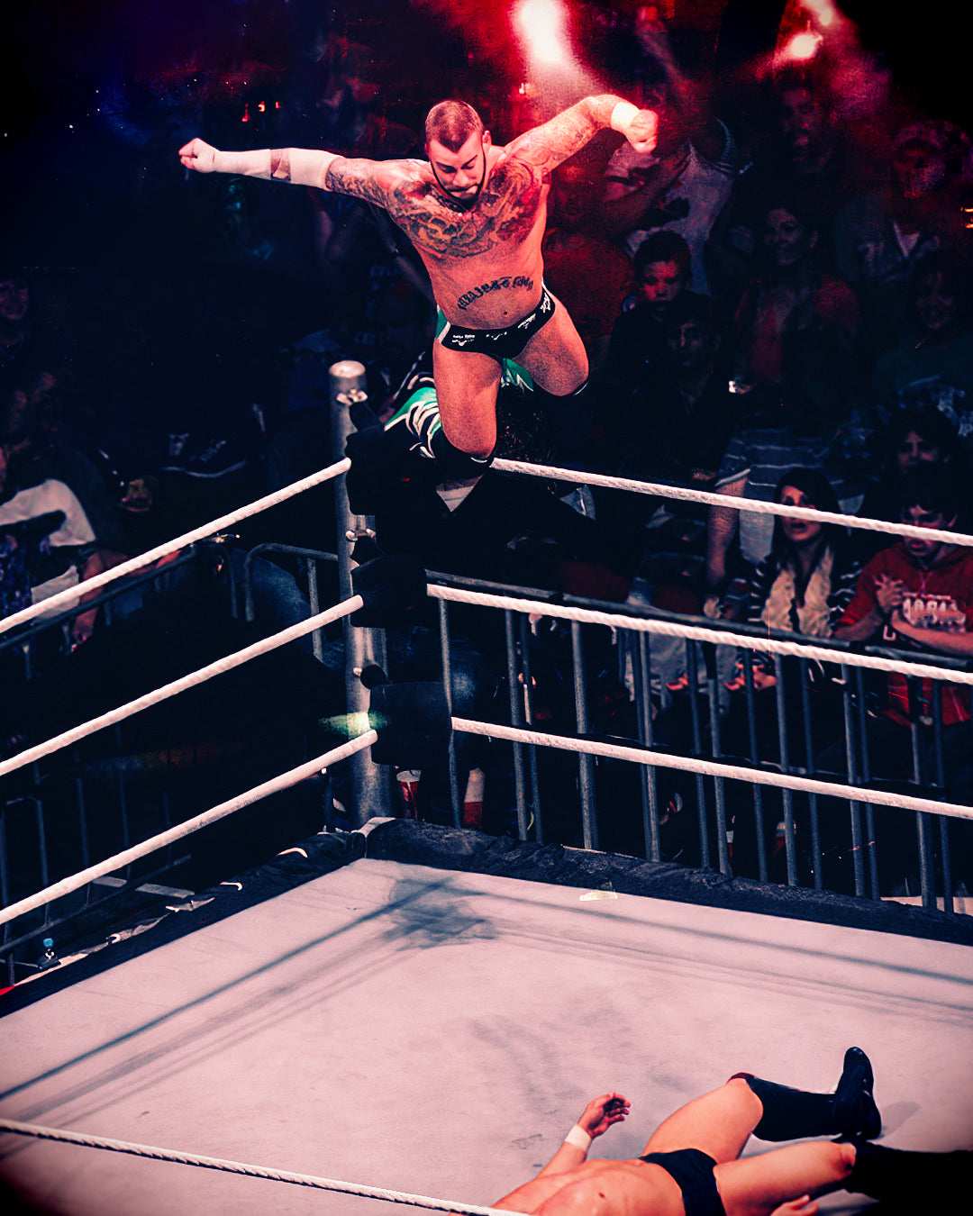 CM Punk wrestler jumps from the turnbuckle onto an opponent in a wrestling ring