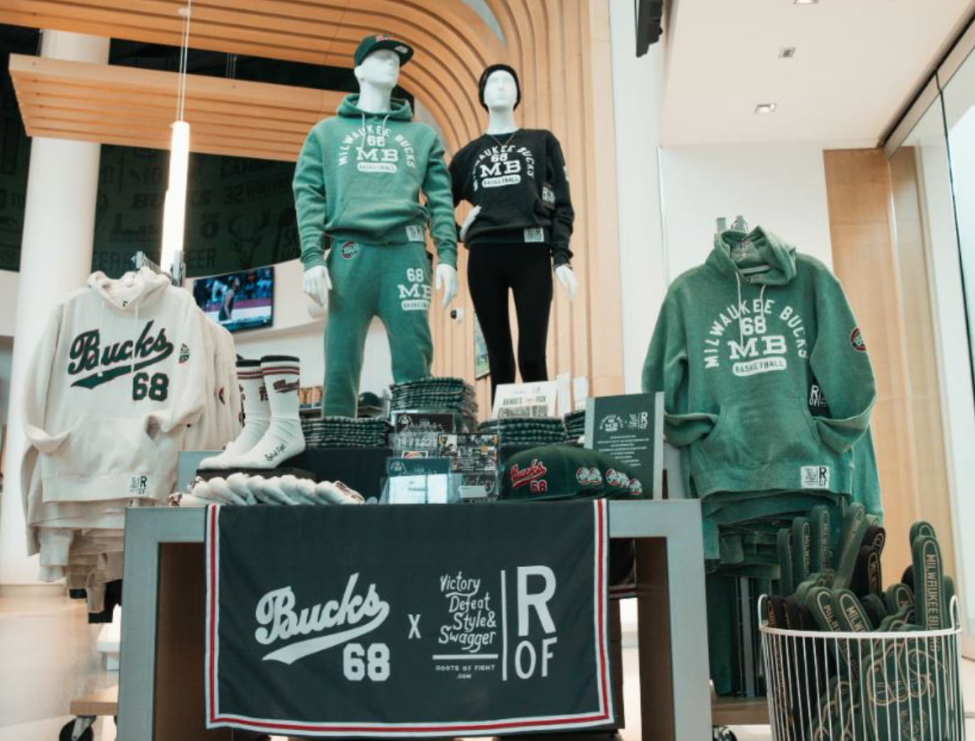Milwaukee Bucks merchandise display featuring hoodies, caps, and socks.
