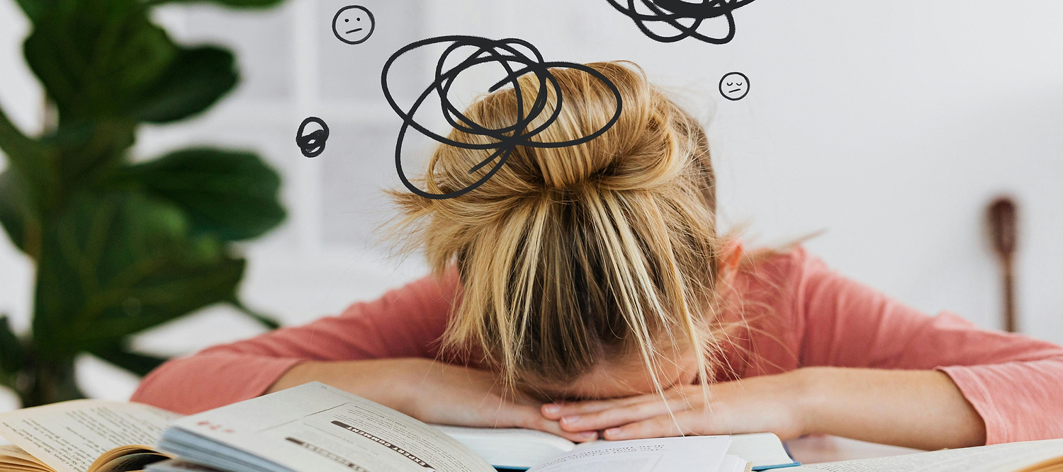 Student resting head on open book with doodled swirl icons overhead, representing brain fog before period and trouble concentrating.