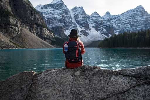 Backpacking woman sitting at the Alpine Lake.