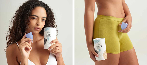 Woman holding a reusable menstrual cup and packaging while wearing yellow shorts in a studio setting.