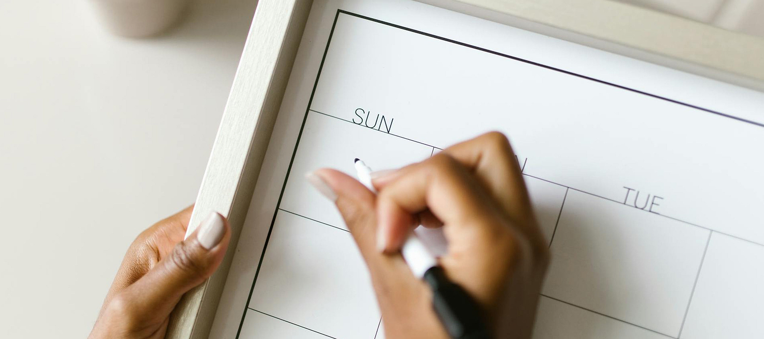 Close-up of a person writing on a calendar for tracking when are you least likely to get pregnant.