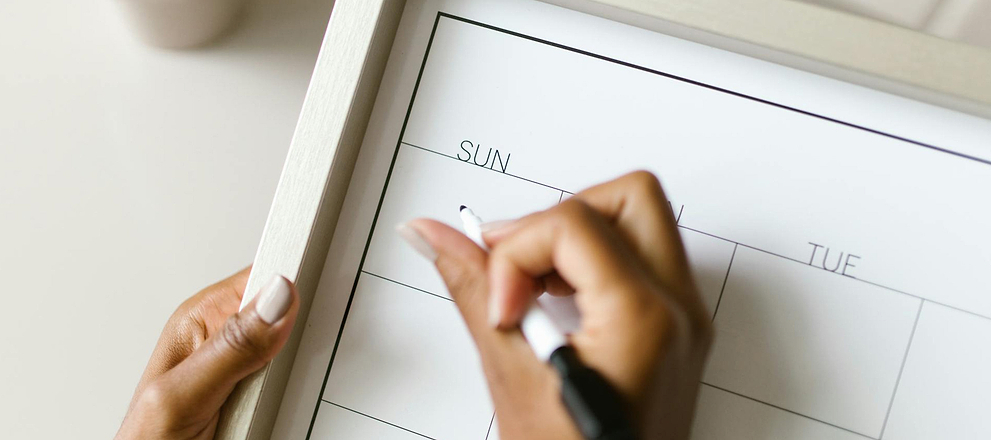 Close-up of a person writing on a calendar for tracking when are you least likely to get pregnant.