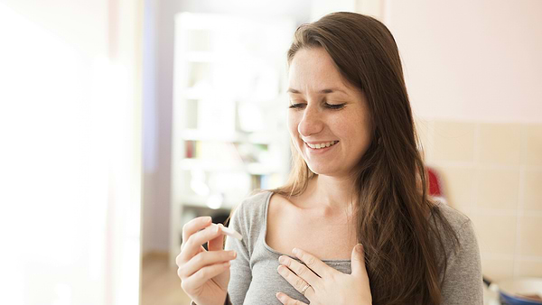 Woman Smiling Happily At Positive Pregnancy Test