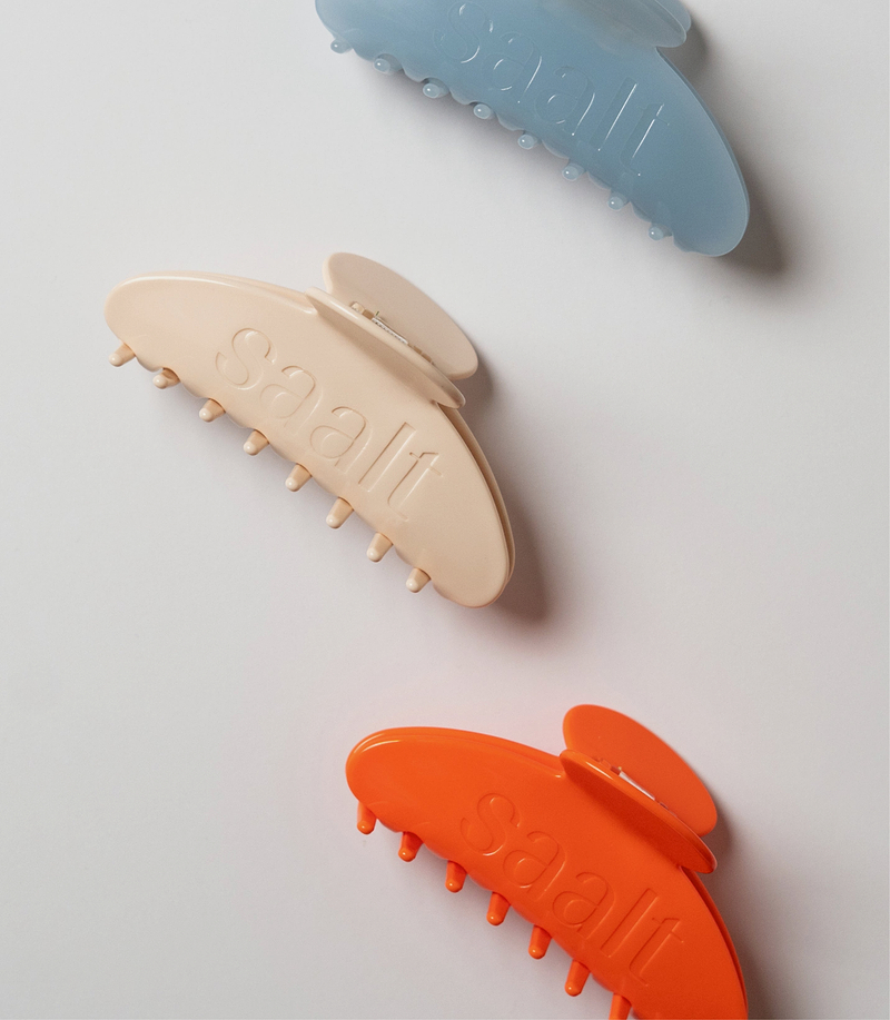 Promotional banner: Spend $100, get a free hair clip. Use code FREECLIP. Beside the text are photos of beige, light blue, and orange Saalt-branded claw hair clips..
