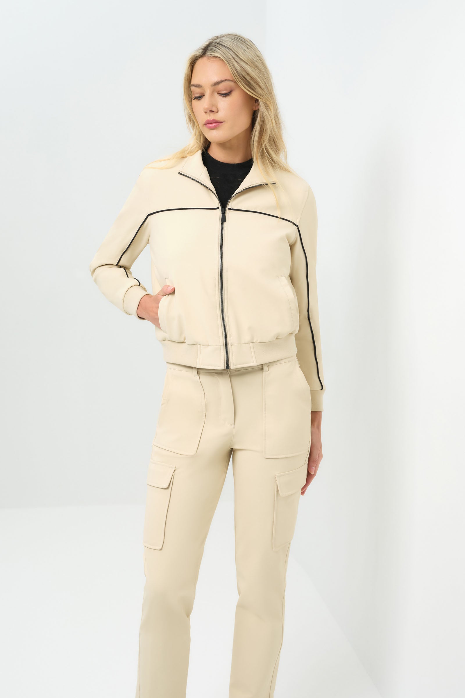 Font view of cream bomber jacket with black pinstripe detailing zipped up to collar