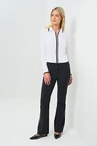 Front view white long-sleeve zip-front blouse featuring a contrasting black trim along the collar, zipper placket, and cuffs. Tailored fit paired with high-waisted black trousers for a clean, modern aesthetic.