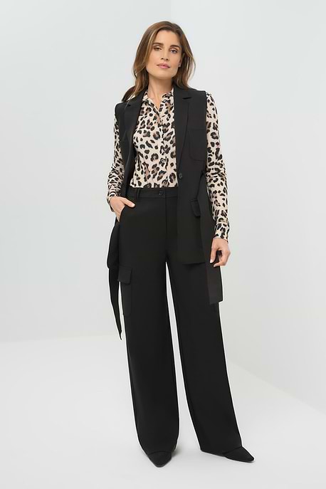 Woman wearing a black suit with a leopard print blouse on a white background