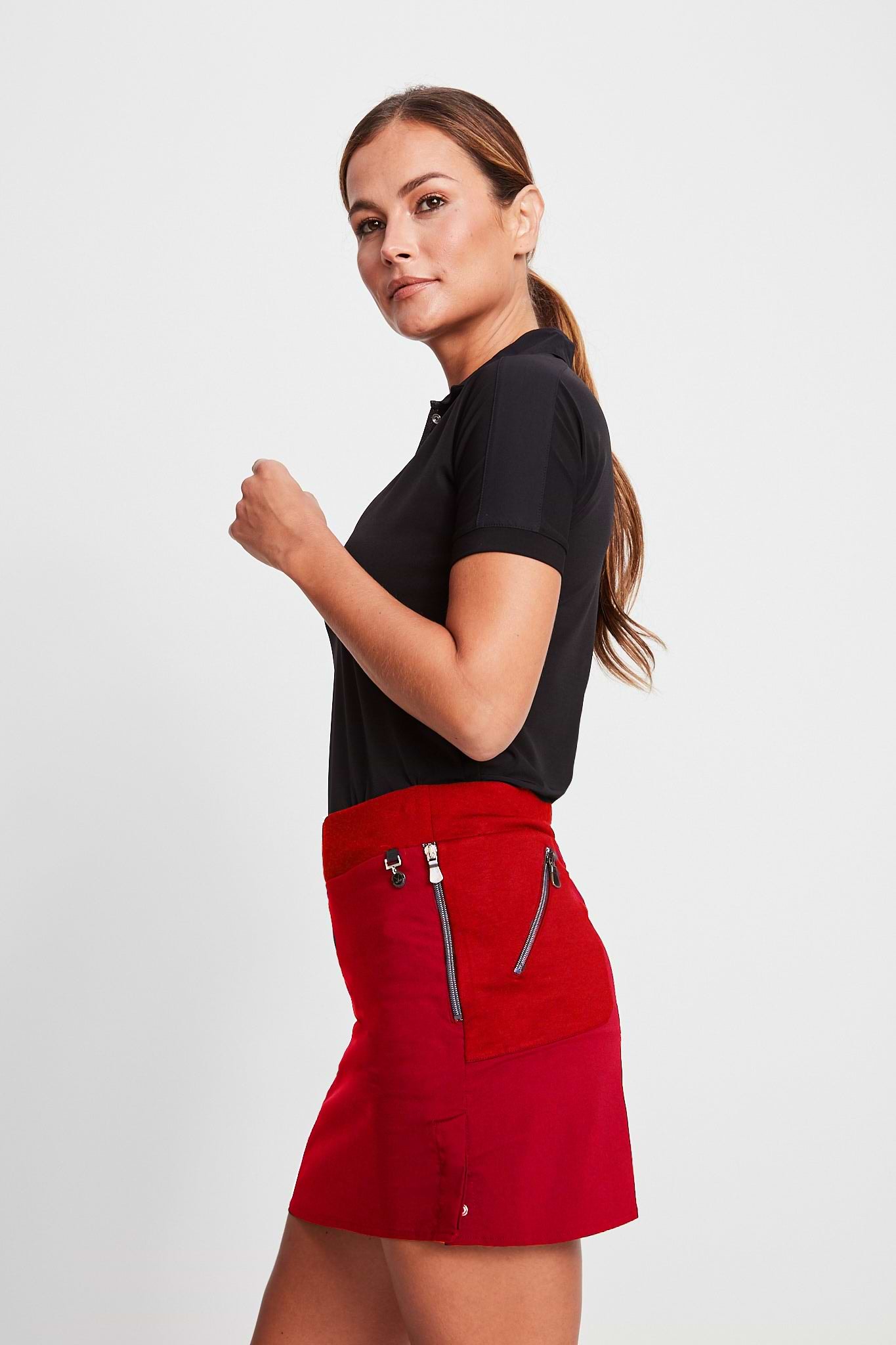 The Best Travel Skort. Woman Showing the Side Profile of a Suzzette Sport Luxe Skort in Atomic Red.
