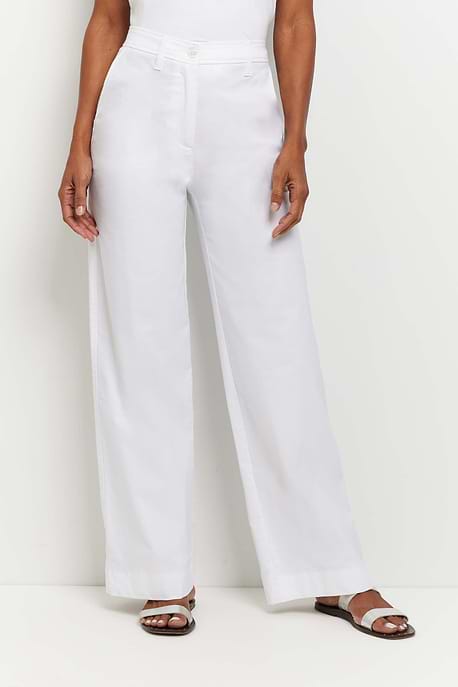 The Best Travel Pants. Woman Showing the Front of a Brooklyn Pant in White.