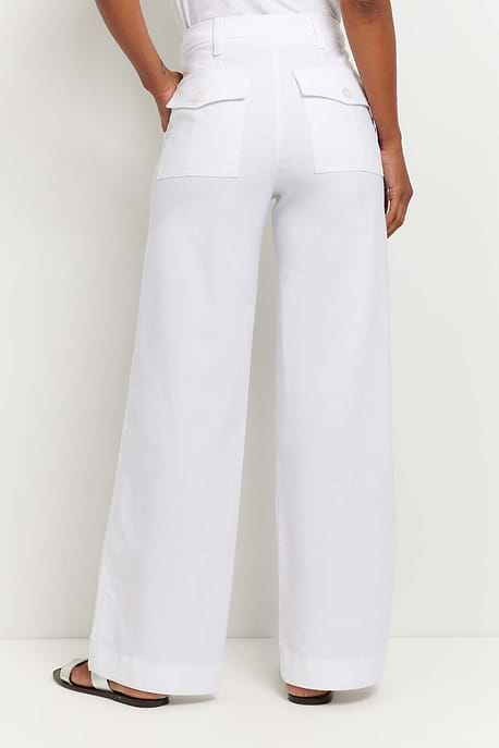 The Best Travel Pants. Woman Showing the Back Profile of a Brooklyn Pant in White.