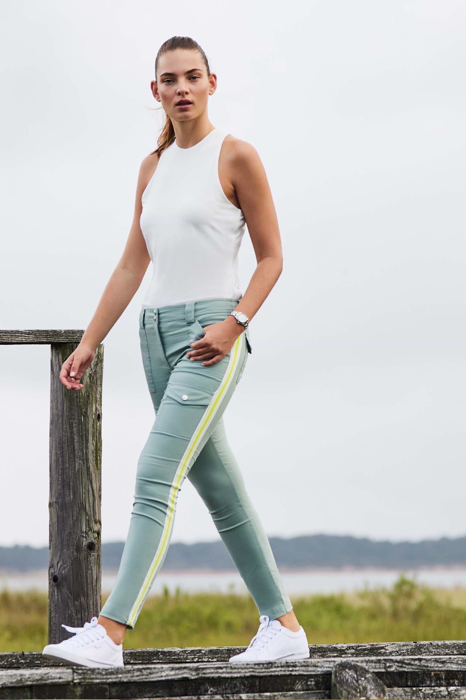 The Best Travel Pants. Lifestyle Image of Woman Showing the Front Profile of a Kate Stripe Pants in Sage.
