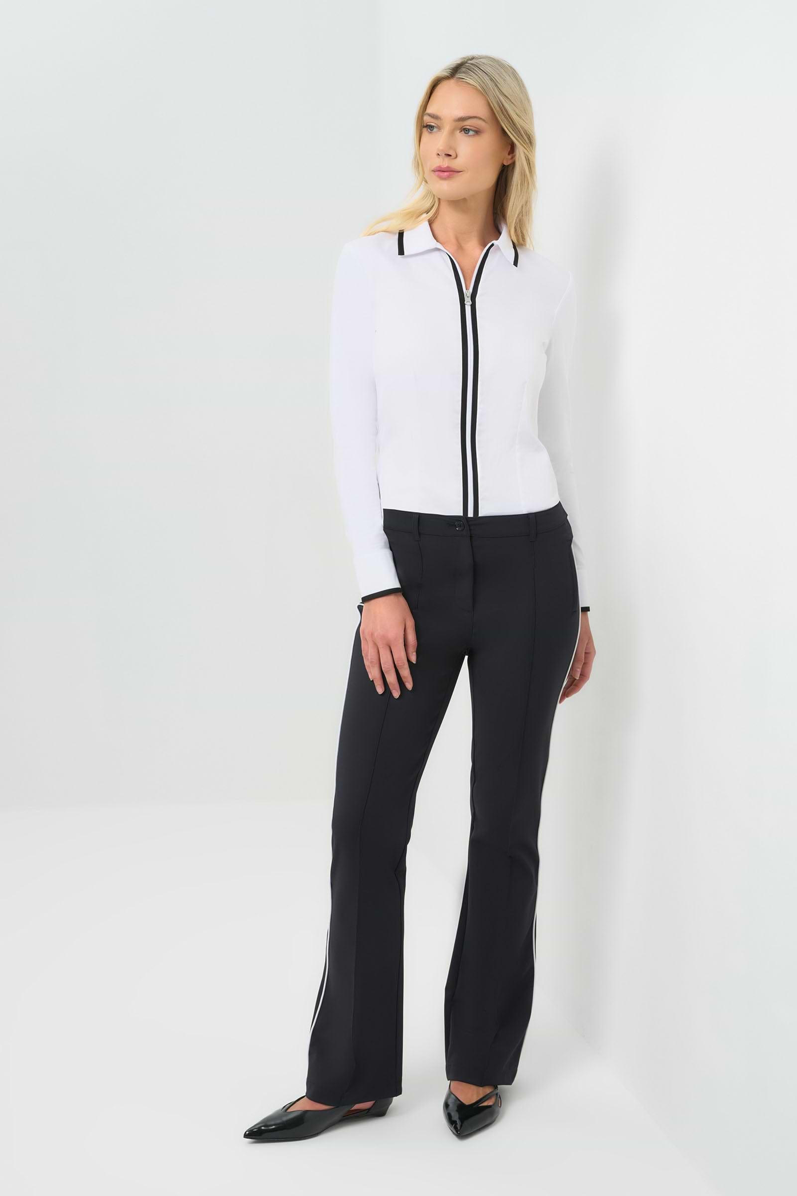 Front view white long-sleeve zip-front blouse featuring a contrasting black trim along the collar, zipper placket, and cuffs. Tailored fit paired with high-waisted black trousers for a clean, modern aesthetic.