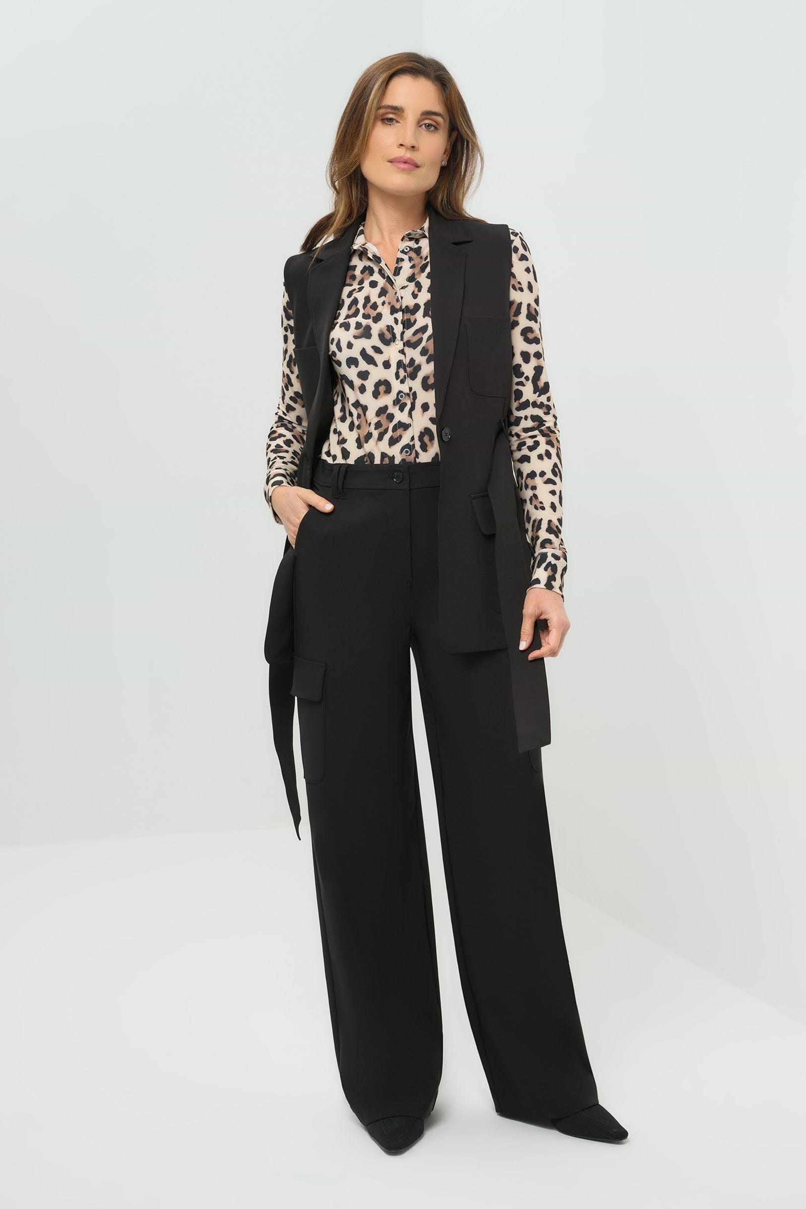 Black vest worn open and untied, paired with a cheetah-print button-down shirt and slim black pants 