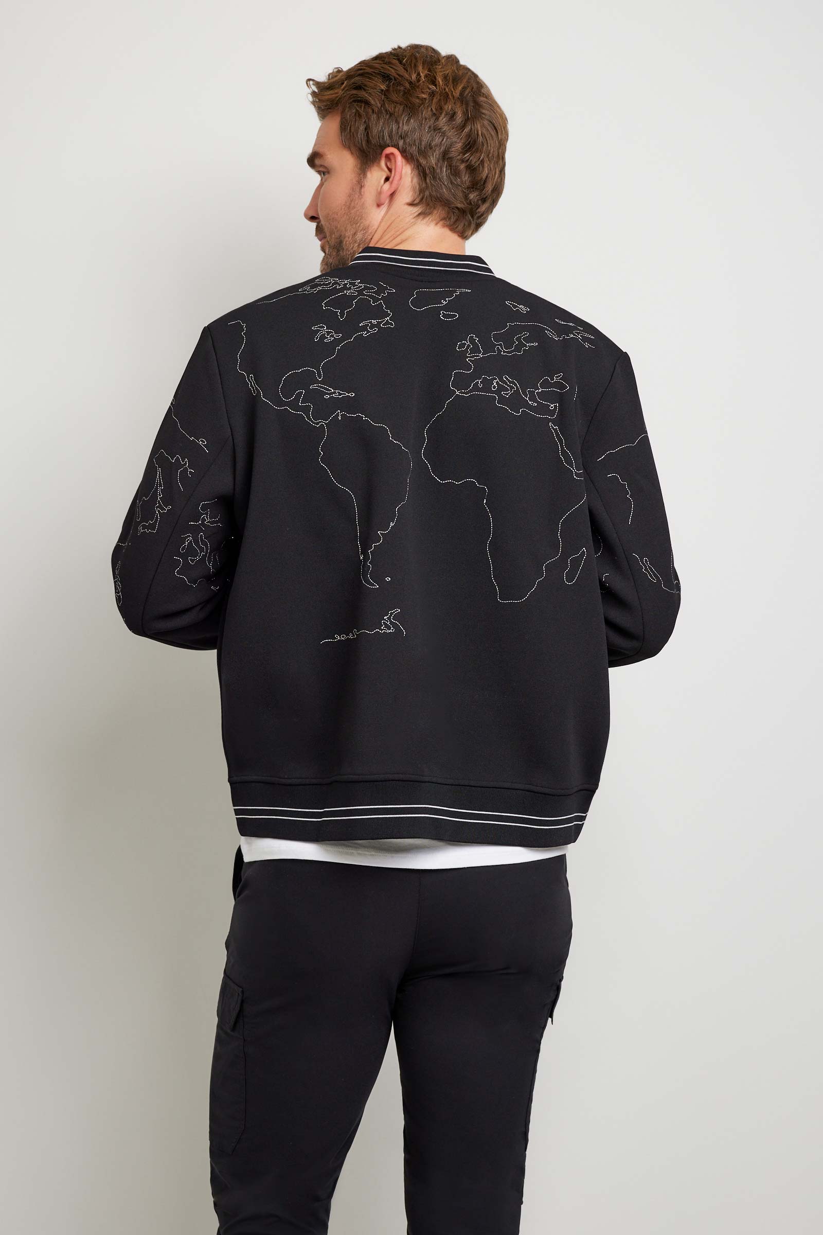 The Best Travel Jacket. Man Showing the Back Profile of a Map Bomber Jacket in Black.
