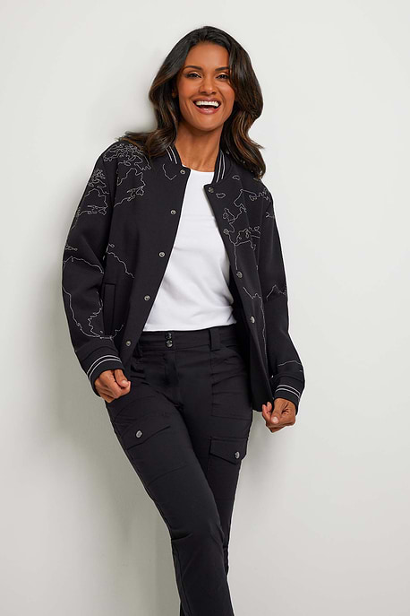 The Best Travel Jacket. Woman Showing the Front Profile of a Map Bomber Jacket in Black.