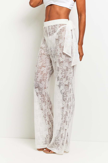 The Best Travel Pants. Woman Showing the Side Profile of a Moana Camo Mesh Pant in White.