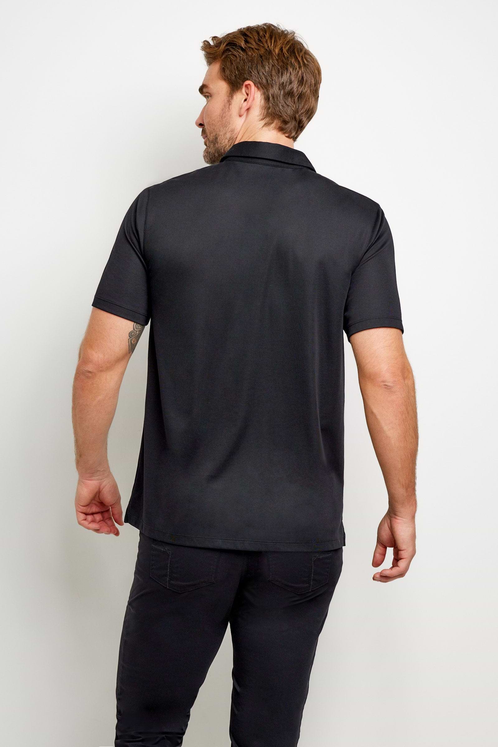 The Best Travel Top. Man Showing the Back Profile of a Men's Ryan Polo in Black.
