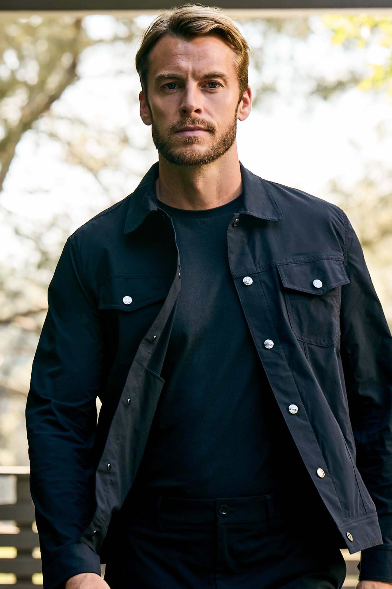 The Best Travel Top. Lifestyle Image of Man Showing the Front Profile of a Men's Scott Top in Black.