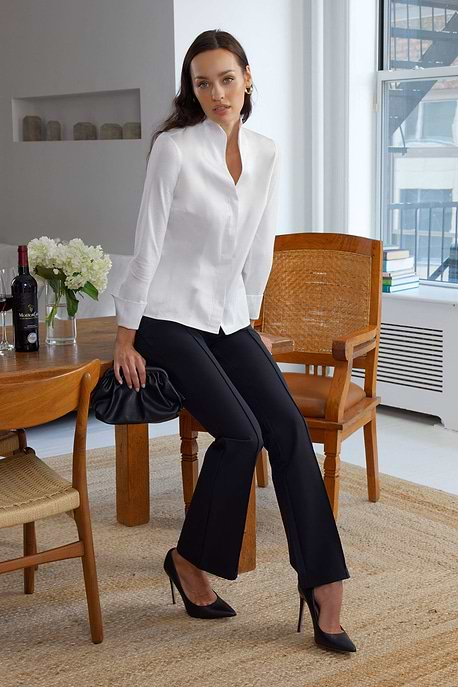 Model wearing the Winny Black Pant by Anatomie, styled with a white blouse and black heels for a chic, polished look in a modern indoor setting.