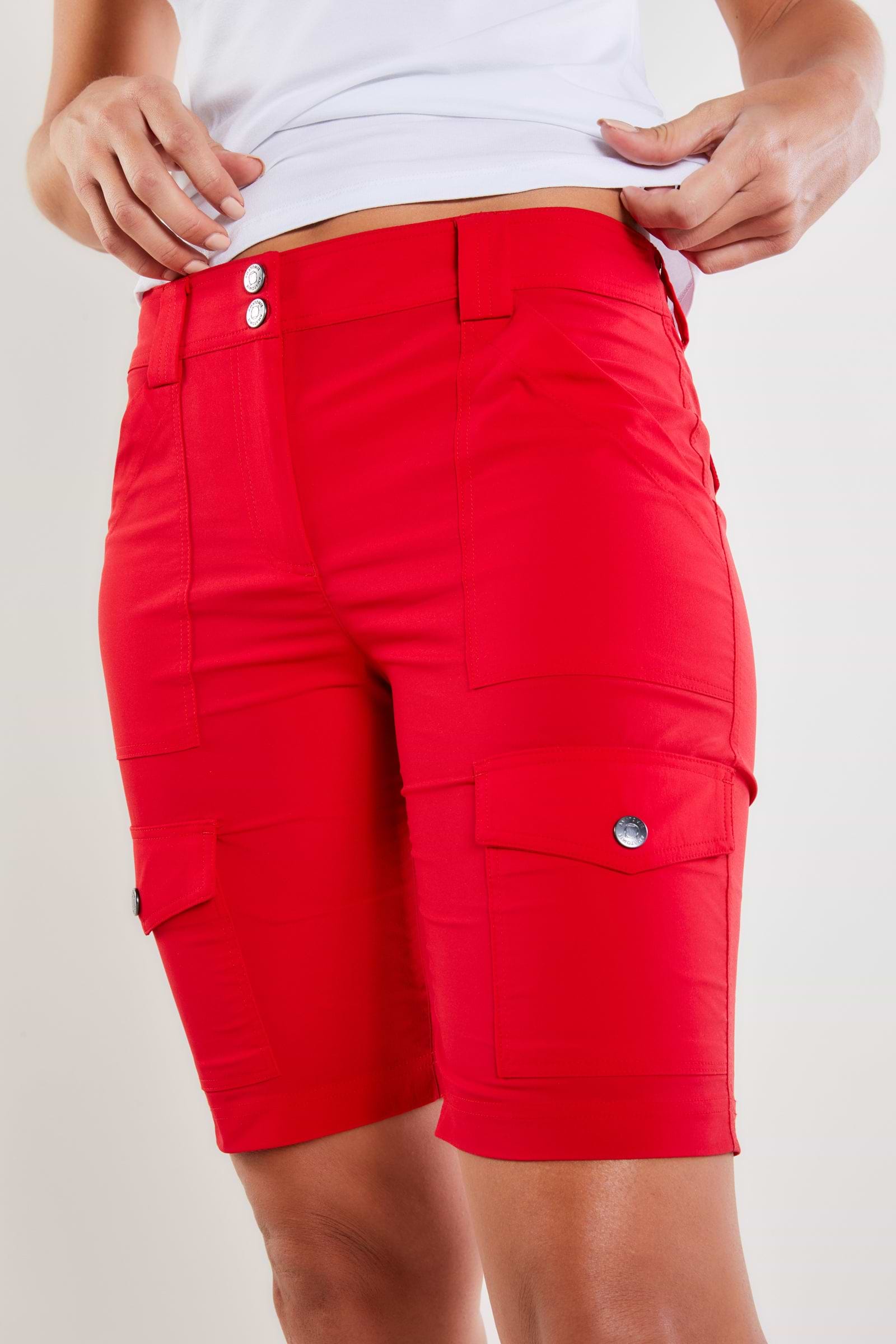 The Best Travel Shorts. Woman Showing the Front Profile of an Apiedi Shorts in Atomic Red.