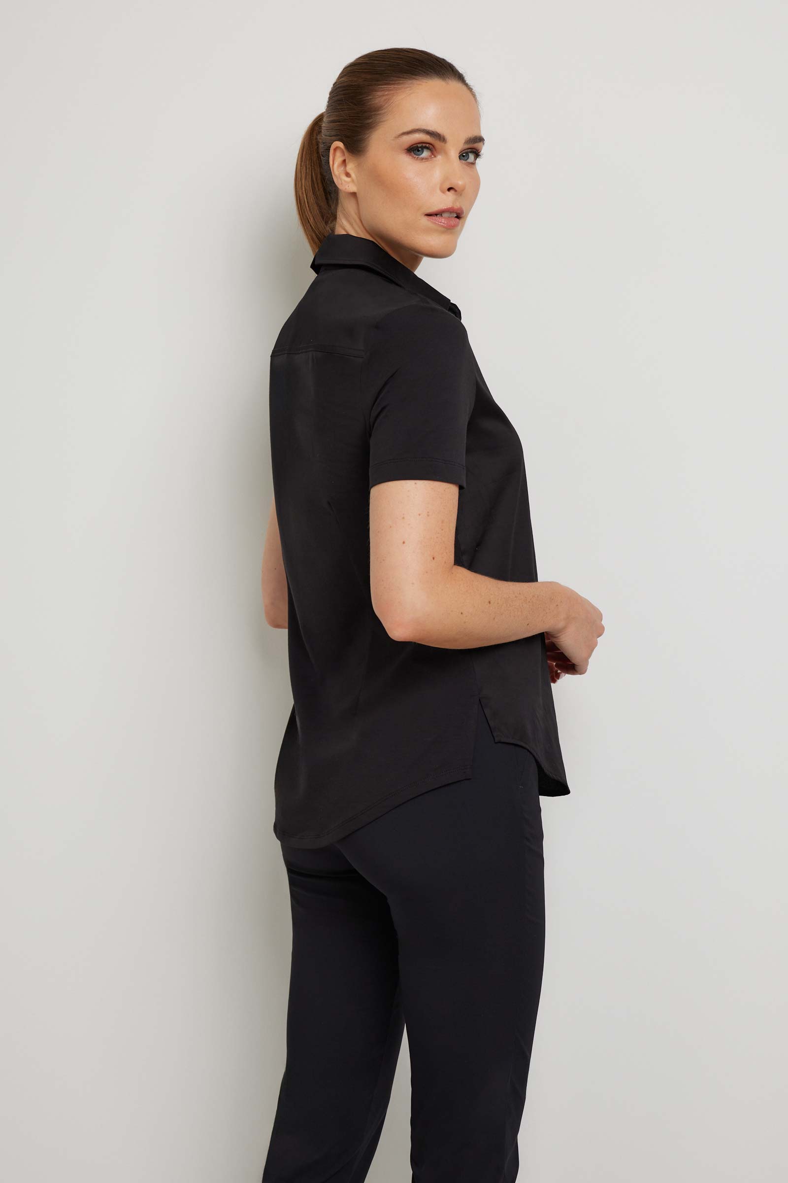 The Best Travel Top. Woman Showing the Side Profile of a Helia Top in Black.