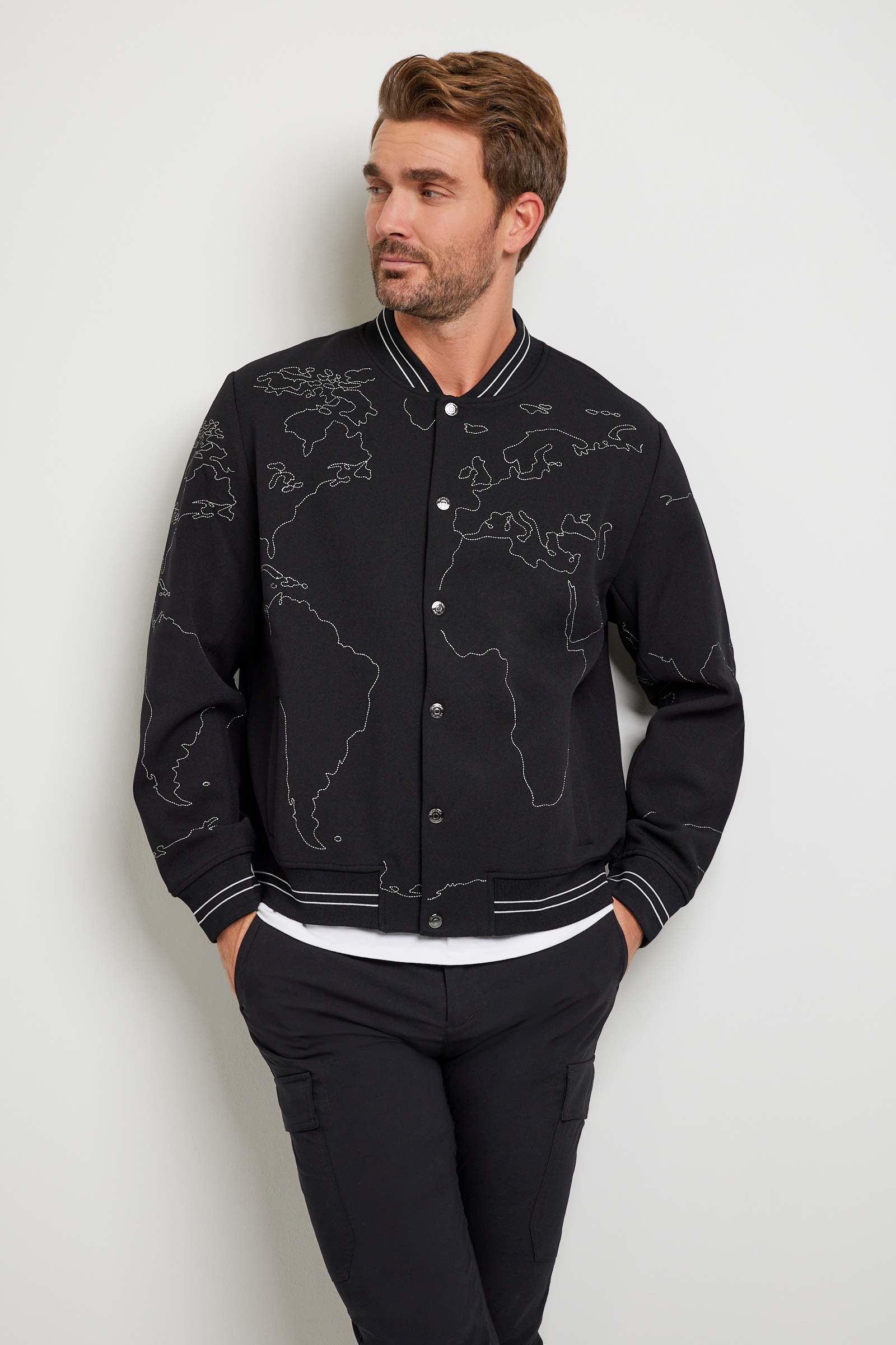 The Best Travel Jacket. Man Showing the Front Profile of a Map Bomber Jacket in Black.