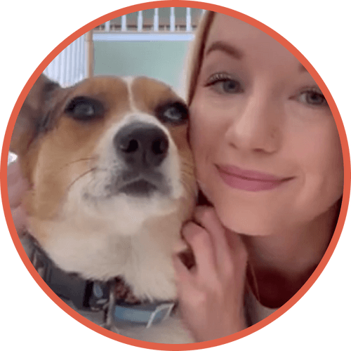 A woman smiling next to her dog inside a home.