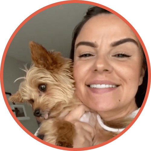 Smiling woman holding a small, fluffy dog.