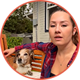 Woman sitting outdoors with a dog on a bench, both looking at the camera.